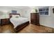 Comfortable bedroom featuring a wooden bed frame, dresser, hardwood floors, and natural light from the windows at 3515 Woodleaf Rd, Charlotte, NC 28205