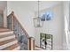 Bright foyer with wood stairs, iron railings, and modern light fixture at 3319 Gresham Pl, Charlotte, NC 28211