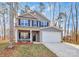 Two story house with gray siding, white garage door, and rocking chairs on the porch at 5510 Brickstone Dr, Charlotte, NC 28227