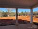 Covered porch with view of wooded backyard and red dirt at 8704 Sherrills Ford Rd, Sherrills Ford, NC 28673