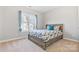 Cozy bedroom with a patterned duvet, wooden bed frame, and natural light from the window at 15613 Glen Miro Dr, Huntersville, NC 28078