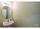 Small half bathroom with pedestal sink and round mirror at 2519 Early Flight Dr, Charlotte, NC 28262