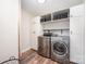 Efficient laundry room featuring modern washer and dryer units, custom cabinets, and shelving at 346 Almora Loop, Mooresville, NC 28115