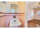 Classic bathroom featuring pink tile, a vintage sink and vanity, and a mirrored wall cabinet at 4017 Leeds Dr, Charlotte, NC 28205