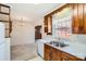 Traditional kitchen featuring wood cabinets, double sink, and natural light from a window with white curtains at 4017 Leeds Dr, Charlotte, NC 28205