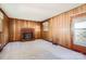 Cozy living room features wood paneling, brick fireplace with mantle and a large window for natural light at 4017 Leeds Dr, Charlotte, NC 28205