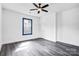 Bright bedroom with gray floors, a ceiling fan, a window with blue trim, and white walls at 8228 Moores Chapel Rd, Charlotte, NC 28214