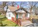 Exterior view of a cozy one-story home with a wooden porch and blue door, surrounded by trees at 8228 Moores Chapel Rd, Charlotte, NC 28214