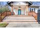 Inviting front porch with wooden steps, decorative pillars, and a bright blue door at 8228 Moores Chapel Rd, Charlotte, NC 28214