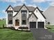 Two-story house with stone and white siding, a two-car garage, and landscaping at Lot 1 Mayes Meadow Dr # Devonshire, Cornelius, NC 28078