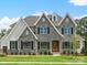 Elegant two-story stone home featuring a three-peaked roof, black shutters, and a well-maintained lawn at Lot 11 Mayes Meadow Dr # Devonshire, Cornelius, NC 28078