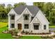 Striking two-story stone home surrounded by lush trees, featuring a well-manicured lawn and professional landscaping at Lot 11 Mayes Meadow Dr # Devonshire, Cornelius, NC 28078