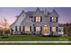 Elegant two-story stone home with a warm glow, complemented by manicured landscaping and a well-maintained lawn at Lot 11 Mayes Meadow Dr # Devonshire, Cornelius, NC 28078