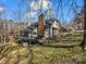 This backyard view showcases the deck, brick chimney, and surrounding greenery at 108 Three Oaks Ln, Kings Mountain, NC 28086