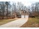 A brick two-story home featuring a two-car garage and long driveway surrounded by trees during the winter season at 122 Ardmore Pl, Mooresville, NC 28117