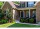 Close-up of a brick two-story home featuring a covered front porch with chairs and manicured landscaping at 122 Ardmore Pl, Mooresville, NC 28117