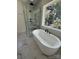 Bright bathroom featuring a soaking tub next to a window and a glass enclosed shower with black hardware at 1912 St John St, Charlotte, NC 28216