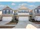 Inviting townhome exteriors showcasing coordinated designs, stone accents, and spacious driveways under a bright, partly cloudy sky at 4134 Steel Way, Sherrills Ford, NC 28673