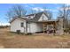 Rear exterior view of the white farmhouse, showcasing the covered patio with outdoor seating and stone fireplace at 4747 Kenneths Dr, Maiden, NC 28650