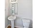 Simple bathroom with a pedestal sink, toilet, and mirror at 6621 Pennacook Dr, Charlotte, NC 28214