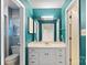 Stylish bathroom with teal wallpaper, decorative mirror and vanity with drawers at 709 Falls Church Rd, Charlotte, NC 28270