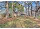 View of a single-story home through the trees with a lawn and a brown mulch ground covering at 709 Falls Church Rd, Charlotte, NC 28270