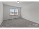 An empty bedroom is brightened by a large window with neutral carpet and freshly painted walls at 8138 Annsborough Nw Dr, Concord, NC 28027