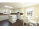 Bright kitchen with white cabinets, tile countertops, white appliances, a breakfast bar, and an eat-in dining area at 134 E Andrews St, Norwood, NC 28128