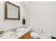 Neutral-toned powder room with a decorative mirror, a pedestal sink, and a toilet at 14500 Harvington Dr, Huntersville, NC 28078
