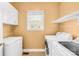 Functional laundry room with white cabinetry, a washer, a dryer, and a window at 14500 Harvington Dr, Huntersville, NC 28078