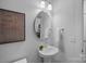 Stylish powder room with pedestal sink, decorative mirror, and modern fixtures at 19765 Feriba Pl, Cornelius, NC 28031