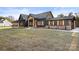 Beautiful modern farmhouse featuring dark siding, stone accents, a covered porch, and an expansive front yard at 2403 Lee Lawing Rd, Lincolnton, NC 28092