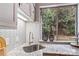 Bright kitchen sink area showcasing a granite countertop and a window offering a view of lush greenery at 7000 Quail Hill Rd, Charlotte, NC 28210