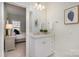 Well-lit bathroom with white vanity, decorative mirror, and a peek into an adjacent bedroom at 1103 N Sharon Amity Rd, Charlotte, NC 28211