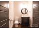 Simple powder room with dark vanity and round mirror at 1725 Dunkirk Dr, Charlotte, NC 28203