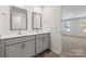 Bright bathroom featuring a double vanity with gray cabinets, light countertops, and two large mirrors at 1758 Falls Cove Rd, Newton, NC 28658