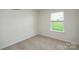 A bright bedroom offers natural light from a window overlooking a verdant lawn and neutral carpeted flooring at 1766 Falls Cove Rd, Newton, NC 28658