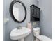 Charming powder room featuring a pedestal sink, decorative mirror, and black storage cabinet at 2000 Shannon Bridge Ln, Matthews, NC 28105