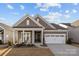 Charming home boasts a covered porch with rocking chairs, complemented by a well-maintained lawn and a two-car garage at 240 Portrait Way # 87, Indian Trail, NC 28079