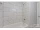 Bright bathroom features a shower and tub combination with marbled tile surround at 3843 Foxford Pl, Charlotte, NC 28215