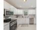 A well-lit kitchen with stainless steel appliances, white cabinets, and stone countertops at 3843 Foxford Pl, Charlotte, NC 28215