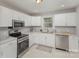 A well-lit kitchen with stainless steel appliances, white cabinets, and stone countertops at 3843 Foxford Pl, Charlotte, NC 28215