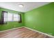 Simple bedroom with green walls, light wood flooring, and two windows at 760 Bethesda Rd, Statesville, NC 28677