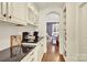 Well appointed white kitchen with black granite countertops and wood floors open to the dining area at 107 E Cold Hollow Farms Dr, Mooresville, NC 28117