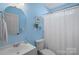 Bright blue bathroom with a clean white vanity, a round mirror, and a shower with a white curtain, offering a fresh and inviting feel at 11414 Coreopsis Rd, Charlotte, NC 28213