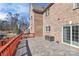 Spacious paver patio with red railing overlooking the backyard, with a view of the home's brick exterior at 4029 Wild Nursery Ct, Charlotte, NC 28215