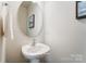 Clean powder room with pedestal sink and round mirror at 7220 Hodges Meadow Ln, Charlotte, NC 28213