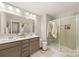 Bright bathroom featuring a double vanity, framed mirror, updated lighting, and a glass-enclosed shower at 14041 Whistling Teal Dr, Charlotte, NC 28262