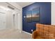 Hallway with a bold blue accent wall featuring modern artwork, adjacent to a comfortable leather chair at 14041 Whistling Teal Dr, Charlotte, NC 28262