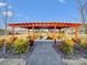 Inviting outdoor space with a red pergola, benches, walkway, and manicured landscaping at 267 Portrait Way, Indian Trail, NC 28079